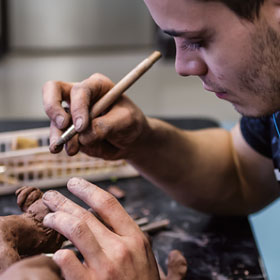 A student manipulating clay with an instrument