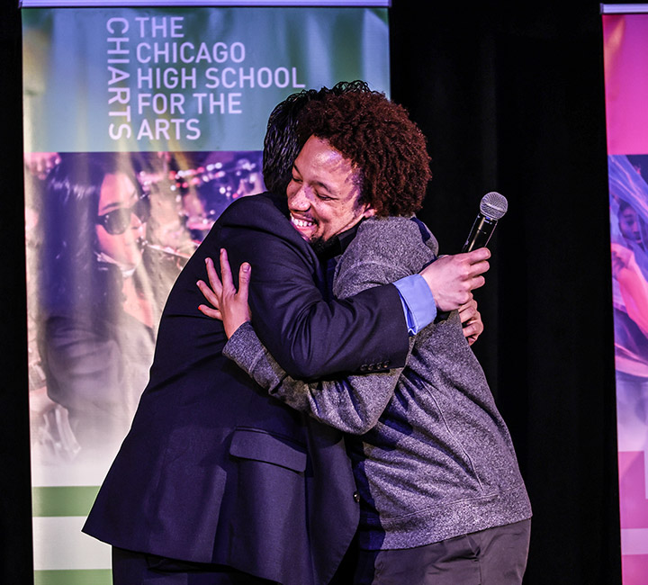 Alumni hugging onstage during an event