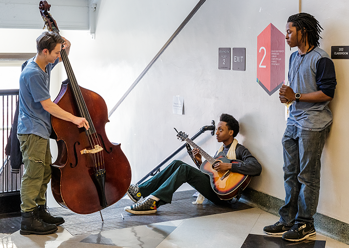 Group of students with musical instruments playing together in the hallway