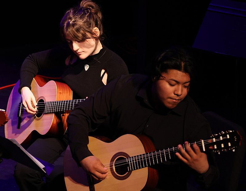 Two students playing guitar onstage